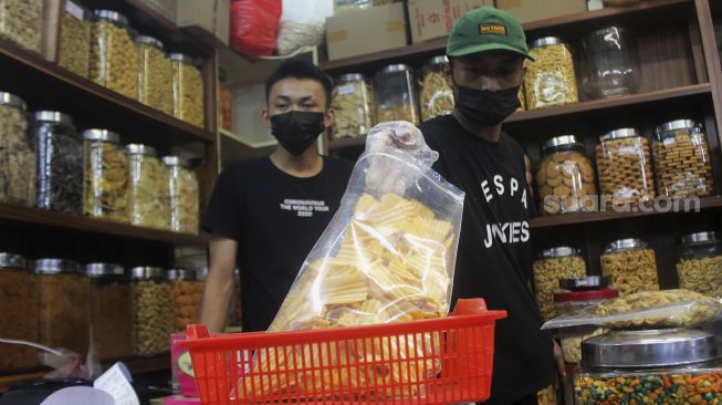 Pedagang melayani pembeli kue kering di Pasar Mester Jatinegara, Jakarta, Minggu (9/5/2021). [Suara.com/Dian Latifah]