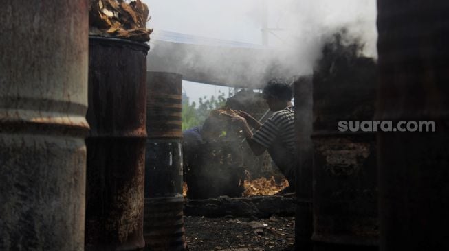 Pekerja memasukkan batok kelapa kering ke dalam keranjang di Kawasan Gang Sentiong, Kramat, Jakarta Pusat, Senin (10/5/2021). [Suara.com/Dian Latifah]