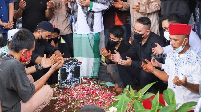 Keluarga dan kerabat berdoa diatas pusara komedian Sapri Pantun di TPU Ulujami, Pesanggrahan, Jakarta Selatan, Selasa (11/5/2021). [Suara.com/Alfian Winanto]