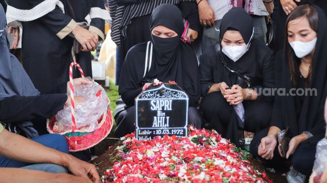 Keluarga berdoa diatas pusara komedian Sapri Pantun di TPU Ulujami, Pesanggrahan, Jakarta Selatan, Selasa (11/5/2021). [Suara.com/Alfian Winanto]