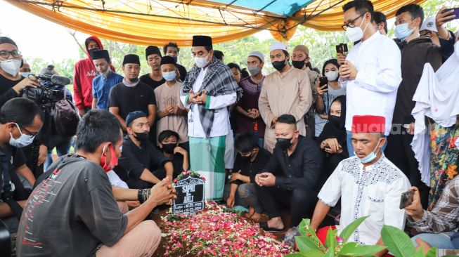 Keluarga dan kerabat berdoa diatas pusara komedian Sapri Pantun di TPU Ulujami, Pesanggrahan, Jakarta Selatan, Selasa (11/5/2021). [Suara.com/Alfian Winanto]