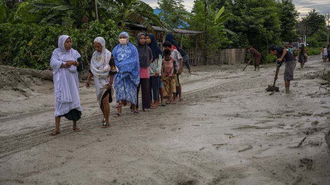 Sejumlah warga melintasi jalan yang tertutup lumpur di Desa Beka, Marawola, Kabupaten Sigi, Sulawesi Tengah, Selasa (11/5/2021). ANTARAFOTO/Basri Marzuki
