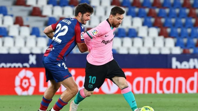 Penyerang Barcelona Lionel Messi (kanan) coba melewati gelandang Levante, Gonzalo Melero dalam laga pekan ke-36 Liga Spanyol di Estadio Ciudad de Valencia, Rabu (12/5/2021) dini hari WIB. [JOSE JORDAN / AFP].