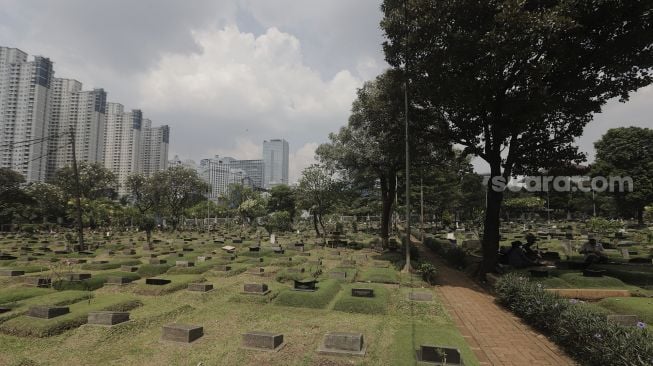 Petugas beristirahat di area makam di Tempat Pemakaman Umum (TPU) Karet Bivak, Jakarta, Rabu (12/5/2021). [Suara.com/Angga Budhiyanto]