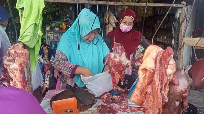 Seorang pedagang daging sapi di Pasar Pagi di Jalan Macan Lindungan, Kelurahan Bukit Baru, Kecamatan Ilir Barat (IB) I Palembang melayani pembeli, Selasa (11/5/2021). [Sumselupdate.com]