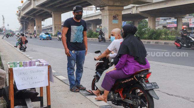 Warga menukar uang ke penjual jasa penukaran uang di Kalimalang, Jakarta Timur, Rabu (12/5/2021). [Suara.com/Alfian Winanto].