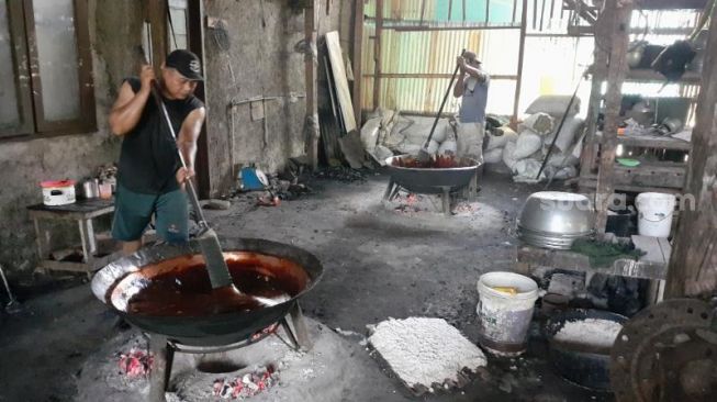 Para pekerja sedang mengaduk adonan Dodol Cilenggang produksi rumahan Titi Mugi Jaya di Cilenggang, Serpong, Kota Tangerang Selatan (Tangsel). [Suara.com/Wivy Hikmatullah]