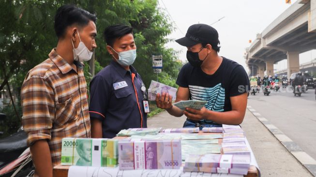 Penjual menawarkan uang baru kepada pembeli di Kalimalang, Jakarta Timur, Rabu (12/5/2021). [Suara.com/Alfian Winanto]