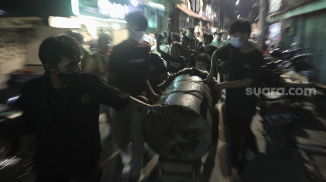 Sejumlah anak menabuh beduk saat takbir keliling di Kecamatan Sawah Besar, Jakarta, Rabu (12/5/2021). [Suara.com/Angga Budhiyanto]