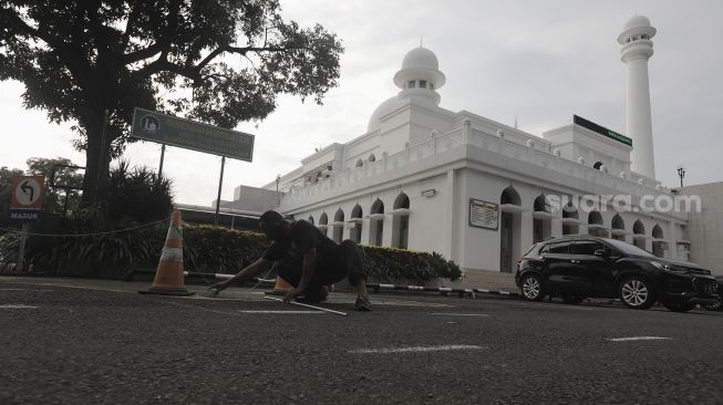 Petugas memberi tanda batas jarak untuk salat Idul Fitri 1442 Hijriah di lapangan Masjid Agung Al-Azhar, Jakarta Selatan, Rabu (12/5/2021). [Suara.com/Angga Budhiyanto]