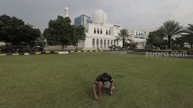 Petugas merapikan jarak untuk salat Idul Fitri 1442 Hijriah di lapangan Masjid Agung Al-Azhar, Jakarta Selatan, Rabu (12/5/2021). [Suara.com/Angga Budhiyanto]