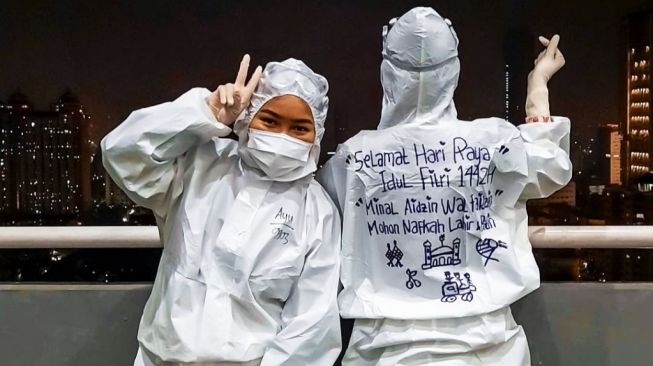 Para tenaga medis di Wisma Atlet Jakarta merayakan Idul Fitri dengan menulis ucapan selamat hari raya Lebaran di baju hazmat mereka pada Rabu (12/5/2021). [Suara.com/Stephanus Aranditio] 