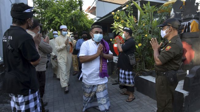 Pecalang dan petugas keamanan lainnya memberi salam kepada umat Islam seusai beribadah Shalat Idulfitri 1442 Hijriah di Mushola Silaturrahmi, Denpasar, Bali, Kamis (13/5/2021). [ANTARA FOTO/Nyoman Hendra Wibowo]