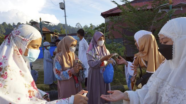 Remaja Masjid Al Mizan (kiri) menyemprotkan handsanitizer dan membagikan masker ke calon jamaah shalat Id di Kota Sorong, Papua Barat, Kamis (13/5/2021). [ANTARA FOTO/Olha Mulalinda]