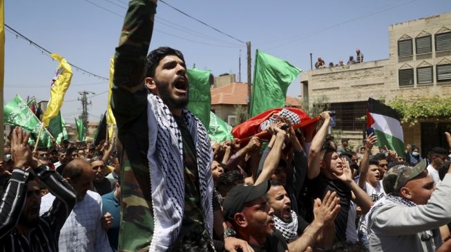 Warga Palestina membawa bendera Hamas saat pemakaman Rashid Abu Ara, remaja 16 tahun yang tewas dalam bentrokan dengan militer Israel di Aqaba, dekat Nablus, Tepi Barat, Rabu (12/5/2021). [AFP/Jaafar Ashtiyeh]