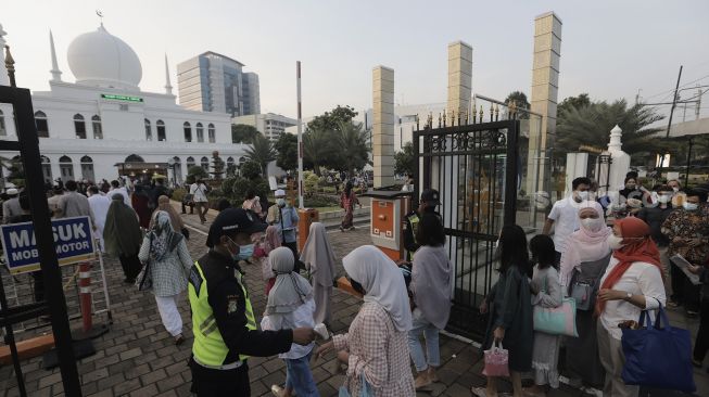 Petugas memeriksa suhu tubuh umat Muslim yang akan menunaikan ibadah Salat Idul Fitri 1442 H di lingkungan Masjid Al-Azhar, Jakarta, Kamis (13/5/2021). [Suara.com/Angga Budhiyanto]