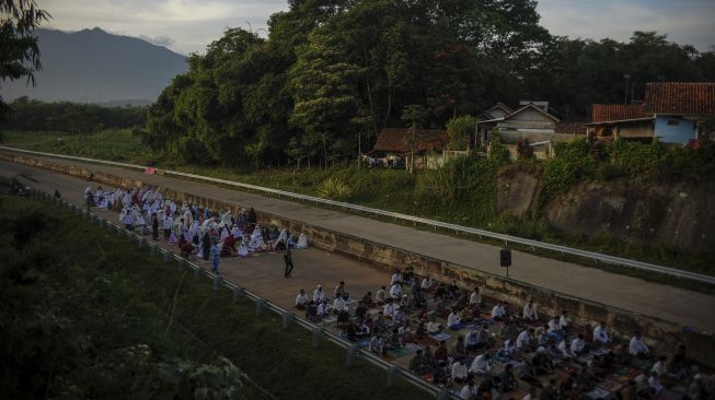 Warga menunggu pelaksanakan Shalat Idul Fitri di ruas Jalan Tol Cileunyi-Sumedang-Dawuan (Cisumdawu) di Pamulihan, Kabupaten Sumedang, Jawa Barat, Kamis (13/5/2021). [ANTARA FOTO/Raisan Al Farisi]