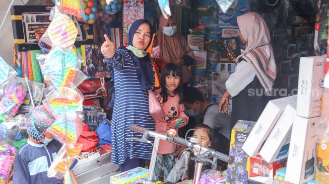 Warga membeli mainan di Pasar Gembrong, Jakarta Timur, Jumat (14/5/2021). [Suara.com/Alfian Winanto]