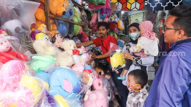 Warga saat membeli boneka di Pasar Gembrong, Jakarta Timur, Jumat (14/5/2021). [Suara.com/Alfian Winanto]