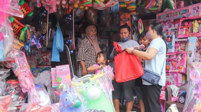 Warga membeli mainan di Pasar Gembrong, Jakarta Timur, Jumat (14/5/2021). [Suara.com/Alfian Winanto]