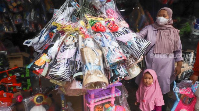 Warga membeli mainan di Pasar Gembrong, Jakarta Timur, Jumat (14/5/2021). [Suara.com/Alfian Winanto]