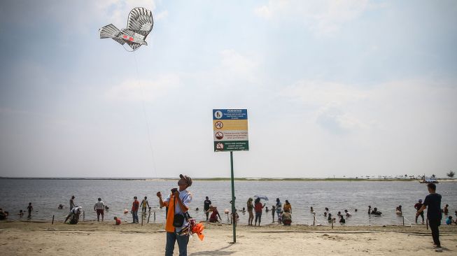 Pedagang menerbangkan layang-layang di Pantai Carnaval Ancol Jakarta, Jumat (14/5/2021). ANTARA FOTO/Rivan Awal Lingga

