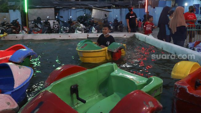 Anak - anak bermain  wahana air di pasar malam BKT (Banjir Kanal Timur) di kawasan Duren Sawit, Jakarta Timur, Sabtu (15/05/2021). [Suara.com/Alfian Winanto]
