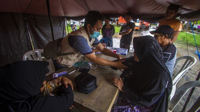 Petugas medis memeriksa kesehatan pengungsi korban banjir di posko kesehatan, Desa Sungai Danau, Kabupaten Tanah Bumbu, Kalimantan Selatan, Sabtu (15/5/2021). [ANTARA FOTO/Bayu Pratama S]