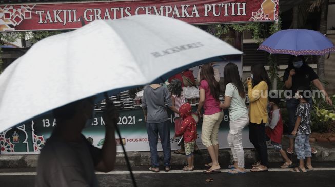 Sejumlah warga mengambil takjil gratis di jalan Cempaka Putih Tengah XXI, Jakarta, Kamis (15/4/2021). [Suara.com/Angga Budhiyanto]