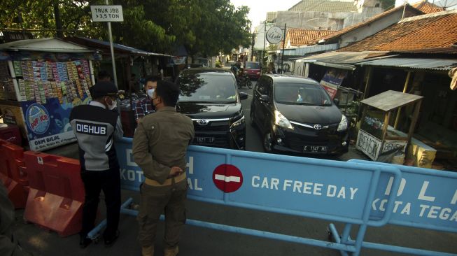 Personel Satpol PP dan Dinas Perhubungan berbincang dengan pengendara yang memaksa masuk di pintu masuk Alun-alun Tegal, Jawa Tengah, Sabtu (15/5/2021). [ANTARA FOTO/Oky Lukmansyah]