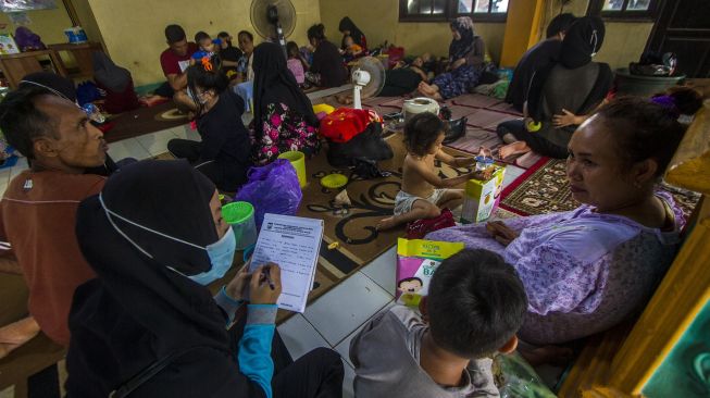 Seorang petugas mendata warga yang mengungsi di posko pengungsian korban banjir di Gedung Majelis Ta'lim Desa Sungai Danau, Kabupaten Tanah Bumbu, Kalimantan Selatan, Sabtu (15/5/2021). [ANTARA FOTO/Bayu Pratama S]