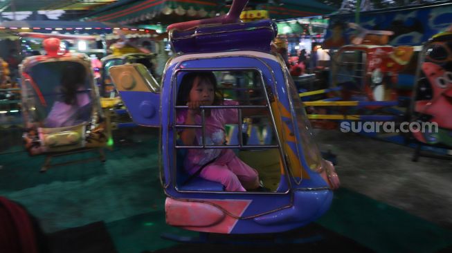 Sejumlah anak bermain di wahana pasar malam BKT (Banjir Kanal Timur) di kawasan Duren Sawit, Jakarta Timur, Sabtu (15/05/2021). [Suara.com/Alfian Winanto]
