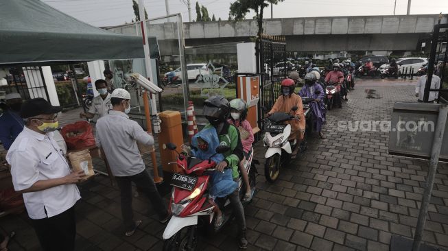 Petugas membagikan takjil kepada pengendara sepeda motor dengan sistem drive thru di kompleks Masjid Al-Azhar, Jakarta, Rabu (14/4/2021). [Suara.com/Angga Budhiyanto]