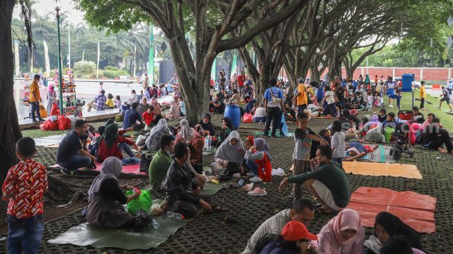 Warga berwisata di sekitar area tugu api Taman Mini Indonesia Indah, Jakarta Timur, Sabtu (15/5/2021). [Suara.com/Alfian Winanto]