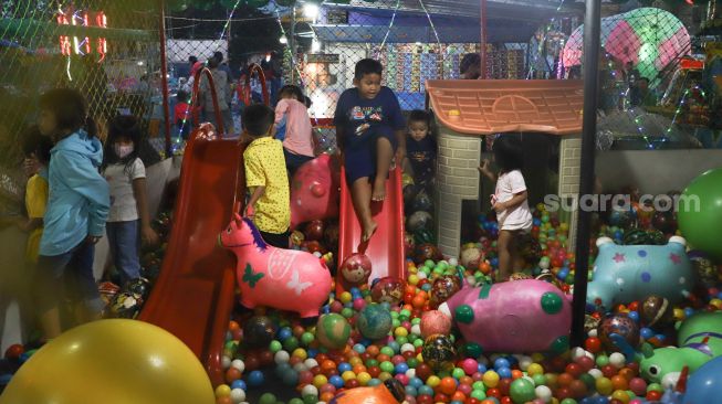 Anak - anak bermain di wahana mandi bola di pasar malam BKT (Banjir Kanal Timur) di kawasan Duren Sawit, Jakarta Timur, Sabtu (15/05/2021). [Suara.com/Alfian Winanto]
