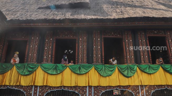 Warga berwisata di anjungan Sumatera Barat Taman Mini Indonesia Indah, Jakarta Timur, Sabtu (15/5/2021). [Suara.com/Alfian Winanto]