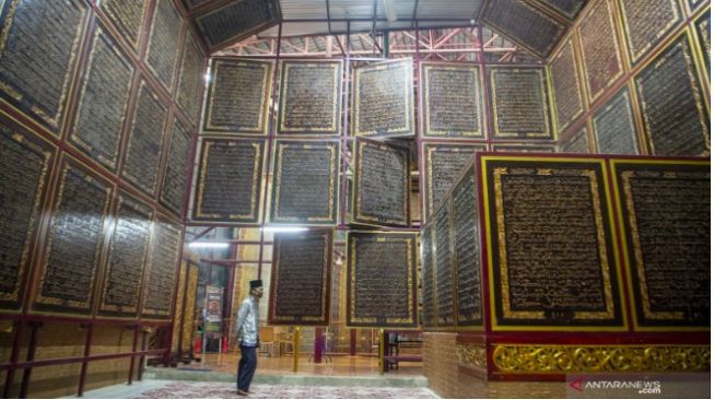 Pengunjung membaca ayat-ayat yang ada di Al Quran Al-Akbar di Palembang, Sumatera Selatan, Jumat (23/4/2021). ANTARA FOTO/Nova Wahyudi/wsj. (ANTARA FOTO/NOVA WAHYUDI) 