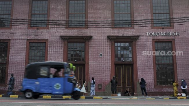 Sejumlah warga berfoto di depan gedung Toko Merah, kawasan Kota Tua, Jakarta, Minggu (16/5/2021). [Suara.com/Dian Latifah]