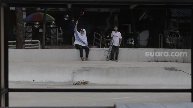 Dua anak bermain di Taman Puring, Kebayoran Baru, Jakarta, Minggu (16/5/2021). [Suara.com/Angga Budhiyanto]
