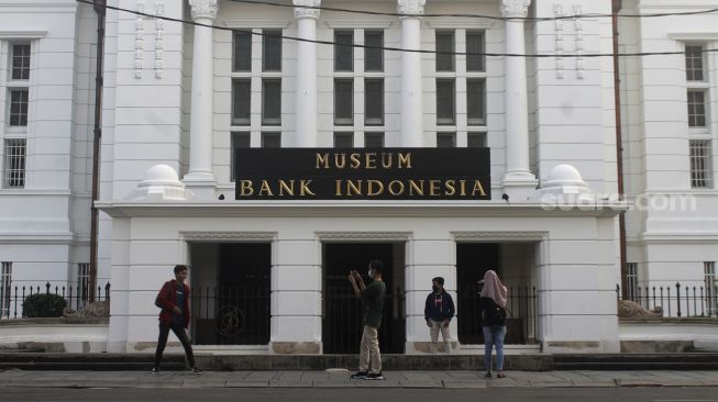 Warga berfoto di depan gedung Museum Bank Indonesia, kawasan Kota Tua, Jakarta, Minggu (16/5/2021). [Suara.com/Dian Latifah]