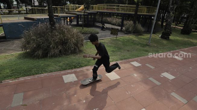 Seorang anak bermain papan seluncur (skateboard) di Taman Puring, Kebayoran Baru, Jakarta, Minggu (16/5/2021). [Suara.com/Angga Budhiyanto]