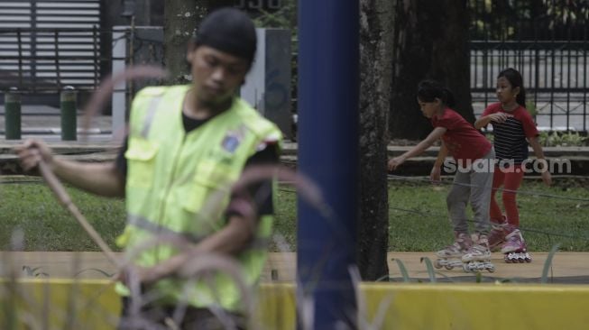 Dua anak bermain sepatu roda di Taman Puring, Kebayoran Baru, Jakarta, Minggu (16/5/2021). [Suara.com/Angga Budhiyanto]