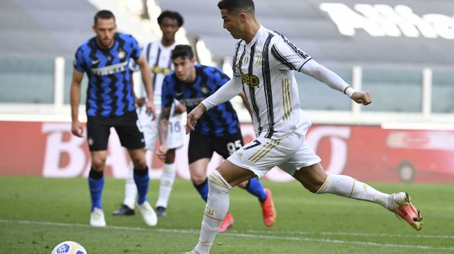 Penyerang Juventus Cristiano Ronaldo melakukan tembakan untuk mencetak gol penalti dan membuka skor selama pertandingan sepak bola Serie A Italia Juventus vs Inter di stadion Juventus, Turin, pada (15/5/2021). [Isabella BONOTTO / AFP]