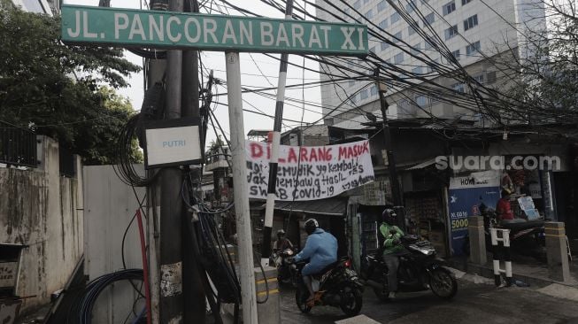 Pengendara melintas di dekat spanduk peringatan untuk pemudik di Jalan Pancoran Barat XI, Jakarta, Senin (17/5/2021). [Suara.com/Angga Budhiyanto]