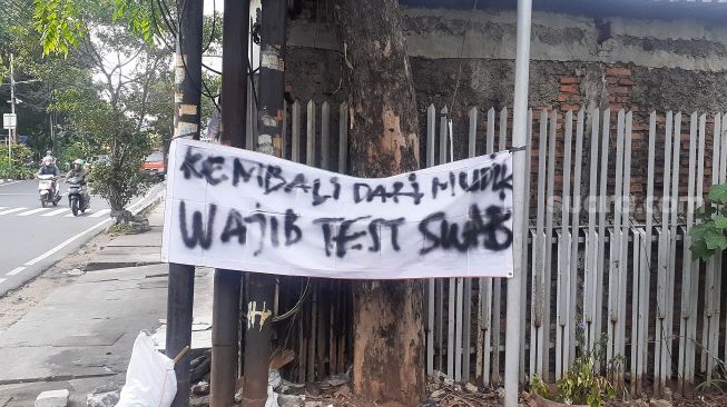 Spanduk tolak pemudik tanpa surat bebas Covid-19 terpasang di akses masu Jalan Kartini XIII Dalam, Kelurahan Kartini, Sawah Besar, Jakarta Pusat, Senin (17/5/2021). [Suara.com/Yaumal Asri Adi Hutasuhut]