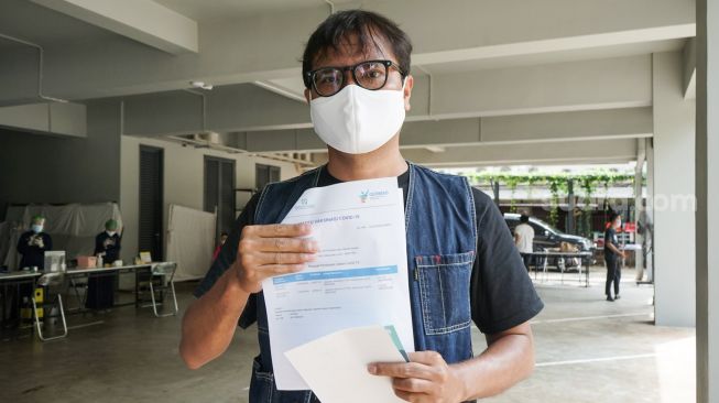 Komika Soleh Solihun menunjukkan sertifikat vaksin usai menjalani vaksinasi Covid-19 tahap dua di Kawasan Pondok Indah, Jakarta Selatan, Senin (17/5/2021). [Suara.com/Alfian Winanto]