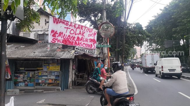 Spanduk tolak pemudik tanpa surat bebas Covid-19 terpasang di akses masu Jalan Kartini XIII Dalam, Kelurahan Kartini, Sawah Besar, Jakarta Pusat, Senin (17/5/2021). [Suara.com/Yaumal Asri Adi Hutasuhut]