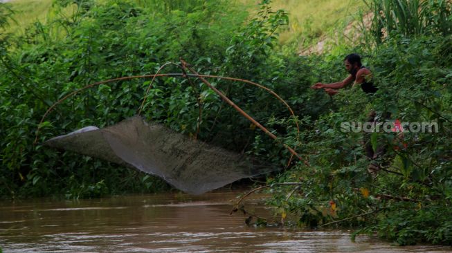 Warga menjaring ikan di Kali Serdang, Bekasi, Selasa (18/5/2021). [Suara.com/Dian Latifah]