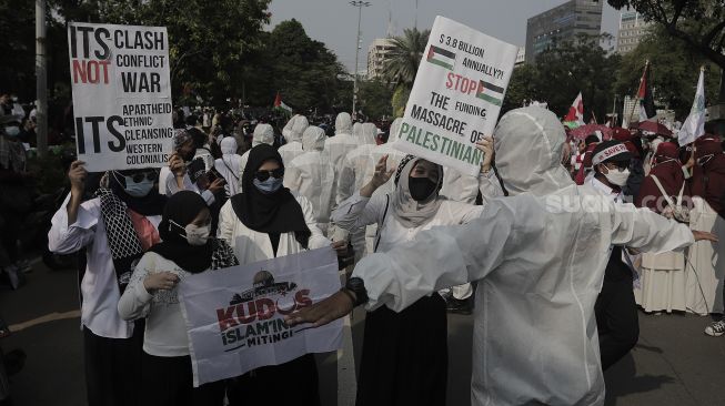 Polisi memakai baju hazmat memberi imbauan kepada massa yang mengikuti aksi solidaritas dukung Palestina di depan Kedubes AS, Jakarta, Selasa (18/5/2021). [Suara.com/Angga Budhiyanto]