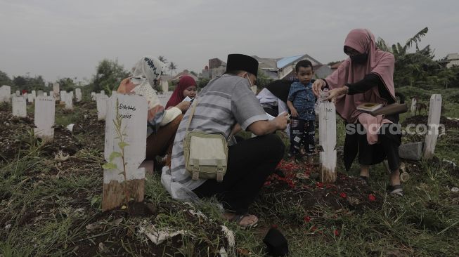 Warga berdoa di makam keluarganya saat melakukan ziarah kubur di pemakaman khusus COVID-19 di TPU Srengseng Sawah, Jakarta, Selasa (18/5/2021). [Suara.com/Angga Budhiyanto]